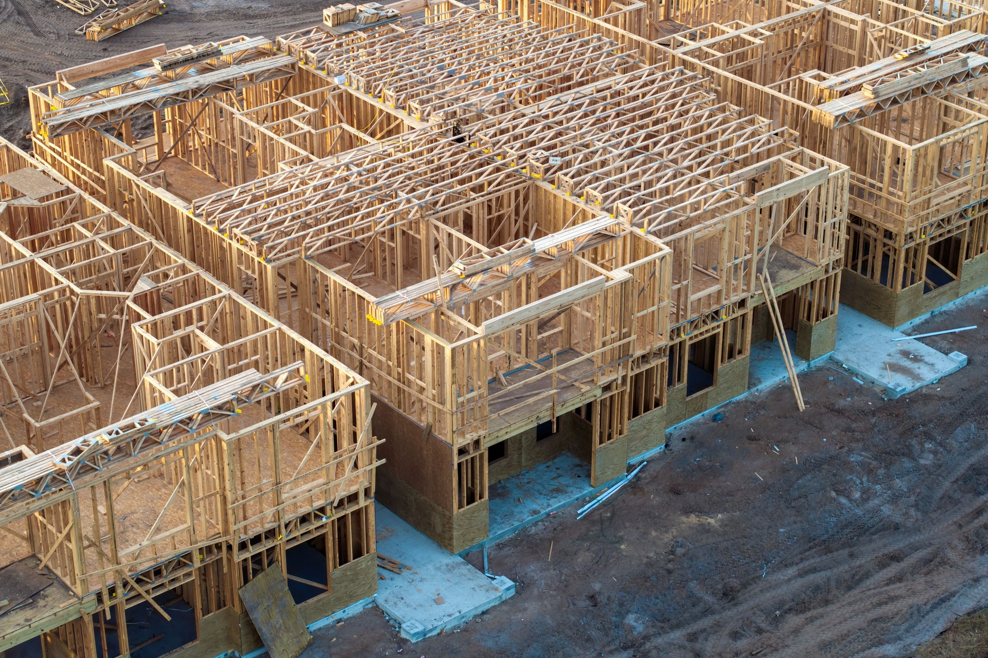 Development of residential housing in American suburbs. Unfinished frames of apartment condos with wooden roof beams under construction. Real estate market in the USA
